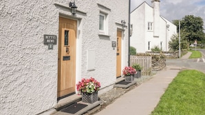 A white building with a wooden door and a sign that reads "BETTYS MEWS 2". - Betty's Loft (Ambleside)