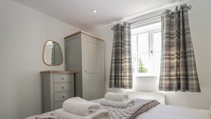 A bedroom with a bed, a wardrobe, a mirror, and plaid curtains. - Betty's Loft (Ambleside)