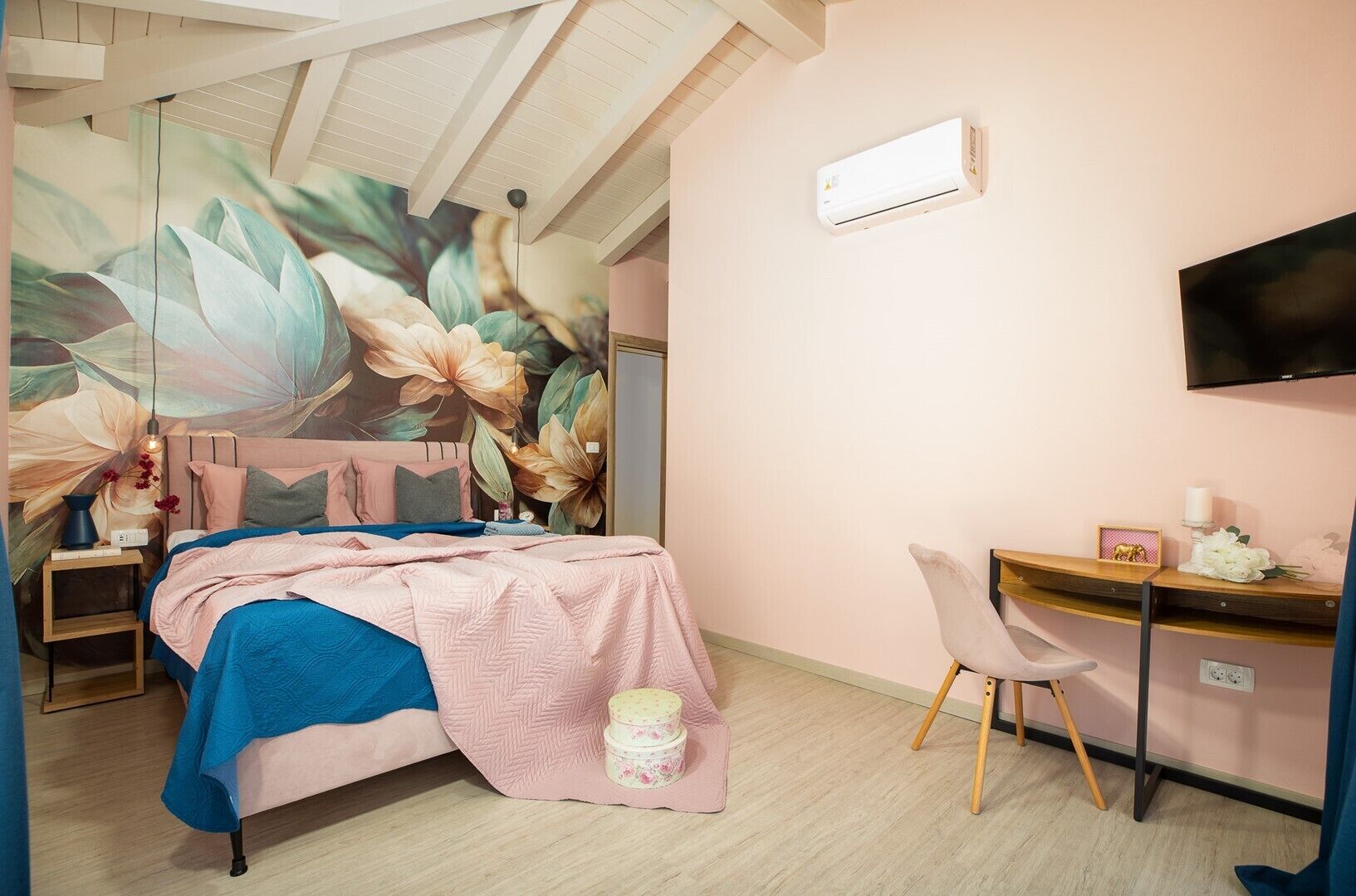 Une chambre à coucher comprenant un lit, un bureau, une chaise, un téléviseur et un climatiseur fixé au mur.