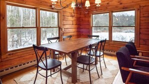 A wooden cabin interior with a dining table, chairs, and a chandelier. - Quiet Cabin On Over 12 Acres Of Woods! (Becket)