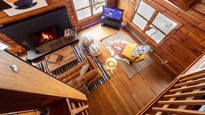 A cozy cabin interior with a fireplace, wooden walls, a television, and a comfortable seating area. - Quiet Cabin On Over 12 Acres Of Woods! (Becket)
