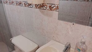 Een badkamer met toilet, wastafel en douche.
