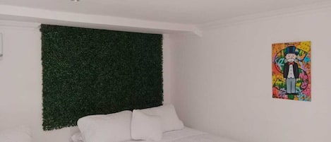 A bedroom with a bed, a green wall panel, and a colorful poster.