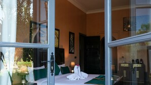 A hotel room with a bed, a nightstand, a lamp, a window with curtains, and a door. - Janat Al Atlas Resort & Spa (Marrakech)