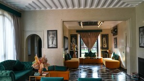 A spacious living area with a green sofa, orange ottoman, and teal armchairs. - Janat Al Atlas Resort & Spa (Marrakech)