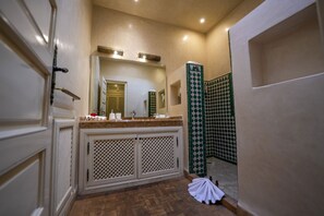 Un baño con tocador, espejo, ducha y azulejos estampados.