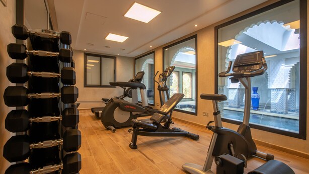 A gym with exercise equipment, a mirror, and large windows. - Janat Al Atlas Resort & Spa (Marrakech)