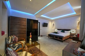Una habitación de hotel moderna con una cama, un sofá, una mesa de centro, un televisor y un televisor de pantalla plana montado en la pared.