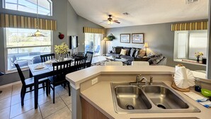 A modern kitchen with a double sink, dining area with chairs, and a view of the outdoors. - Last Minute Disney Getaway! Private Pool, Hot Tub & Game Room. Book Now! #83157 (Orlando)