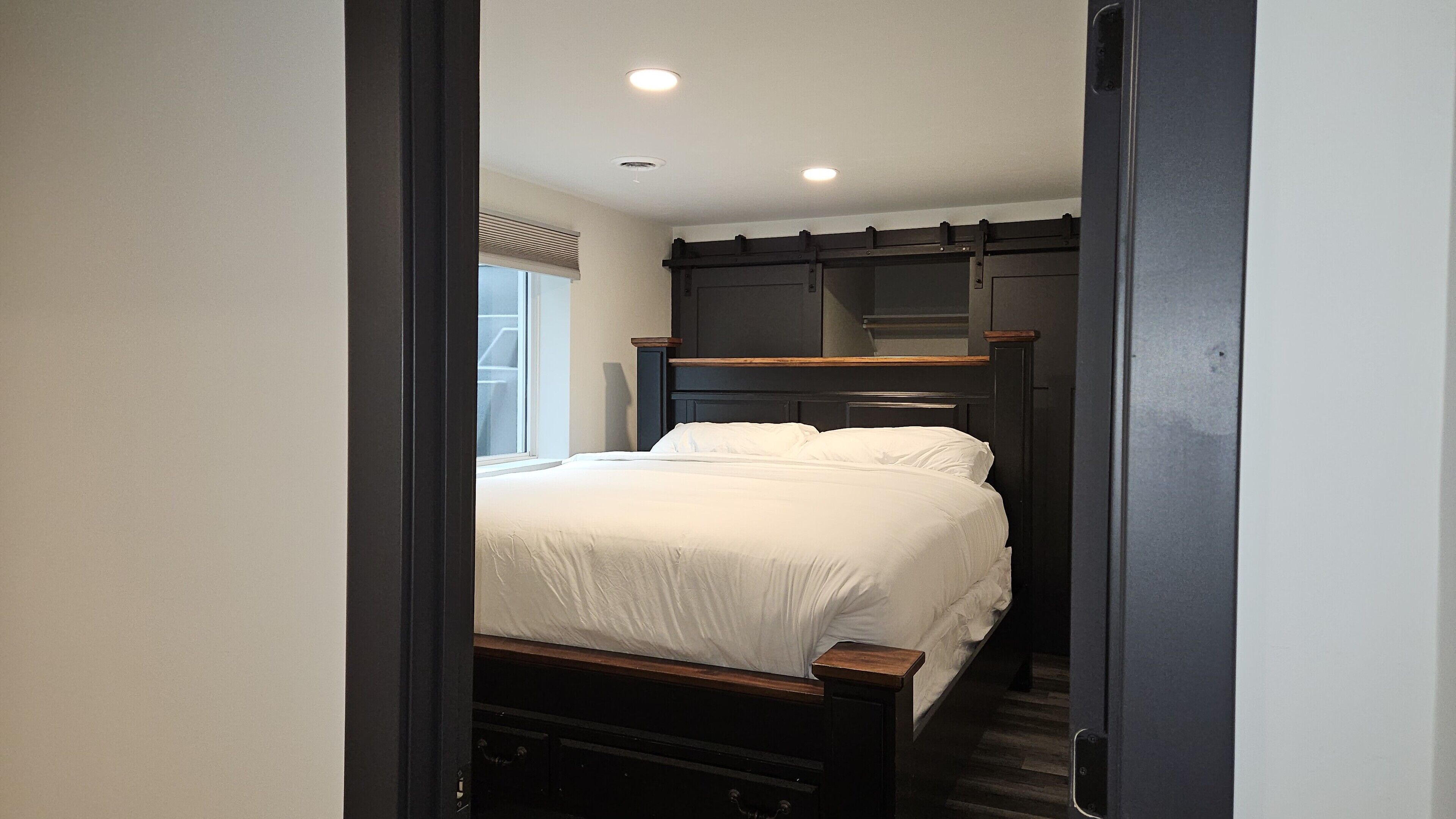 A bedroom with a bed, a window, and a door.