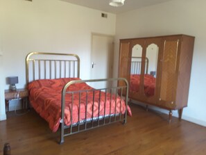 A bedroom with a metal-framed bed, a wooden wardrobe, and a wooden floor. - Emplacement Unique Offrant un Magnifique Panorama Face à la Chaîne Pyrénéenne (Ercé)