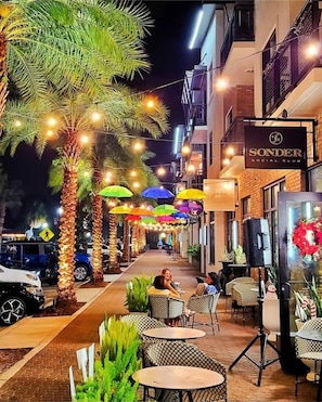 Relax in a tranquil outdoor setting surrounded by palm trees and string lights, perfect for casual dining or socializing.