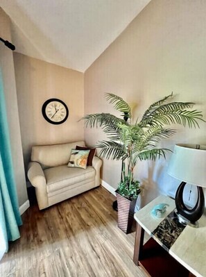 Relax in this inviting living space with a comfortable sofa, potted plant, and warm wooden flooring.