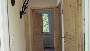 A hallway with wooden doors, a black mat at the entrance, and antler decorations on the wall. - Hellaberg III: Quiet vacation home with sauna on the edge of the forest (Schleusegrund)