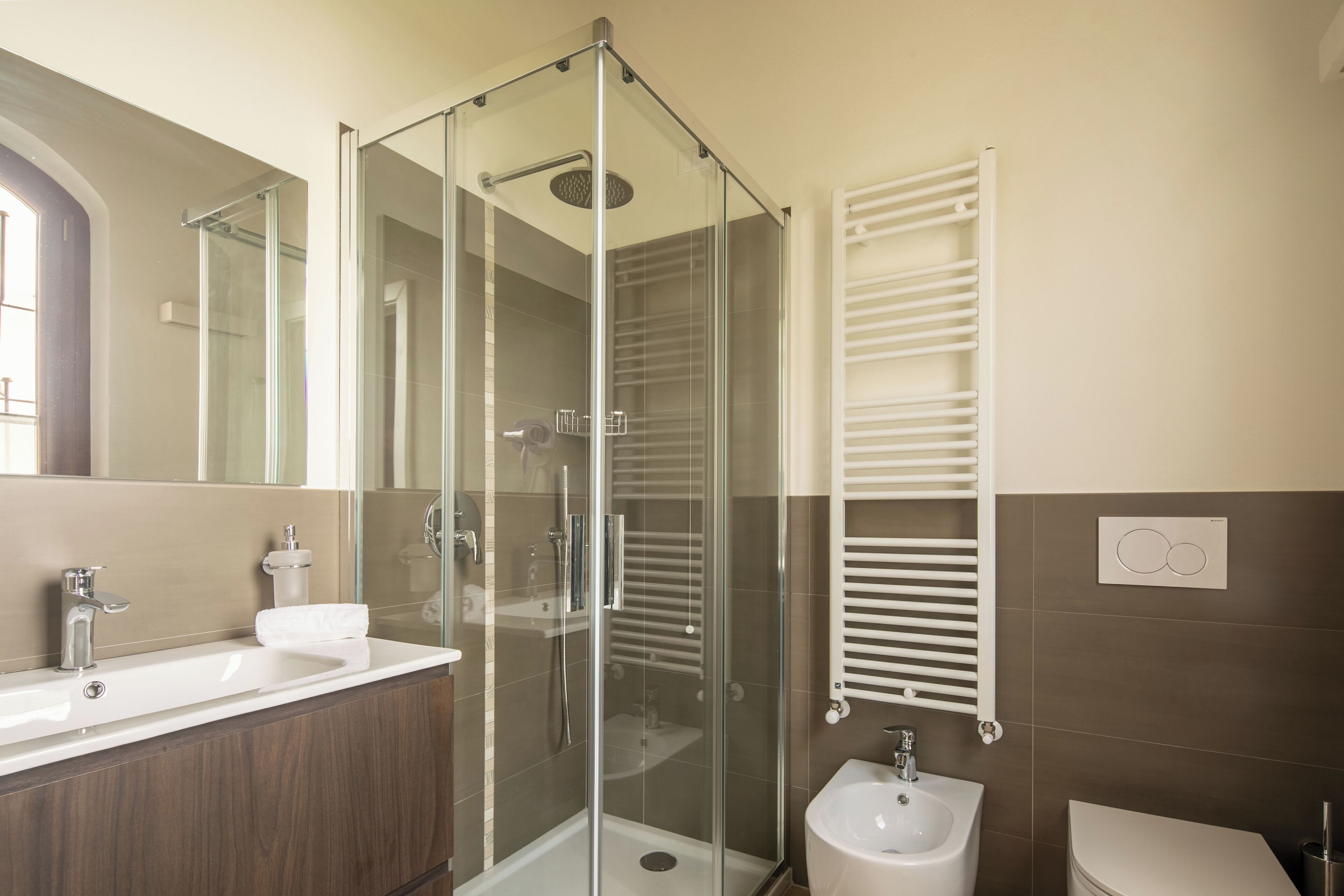 A modern bathroom with a glass-enclosed shower, a sink, a bidet, and a toilet.