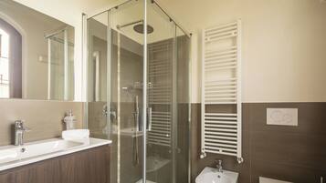 A modern bathroom with a glass-enclosed shower, a sink, a bidet, and a toilet.