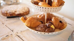 A tray of assorted pastries and a cake on a table with a lace tablecloth. - Podere La Quercia (San Gimignano)