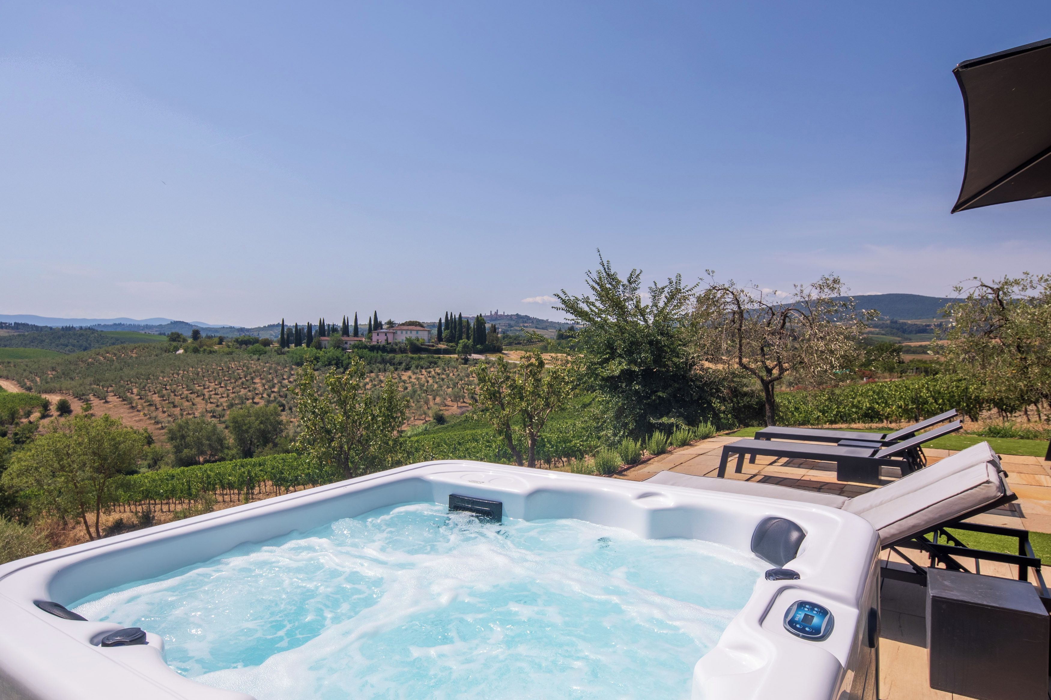 A hot tub with a clear view of vineyards and distant hills.