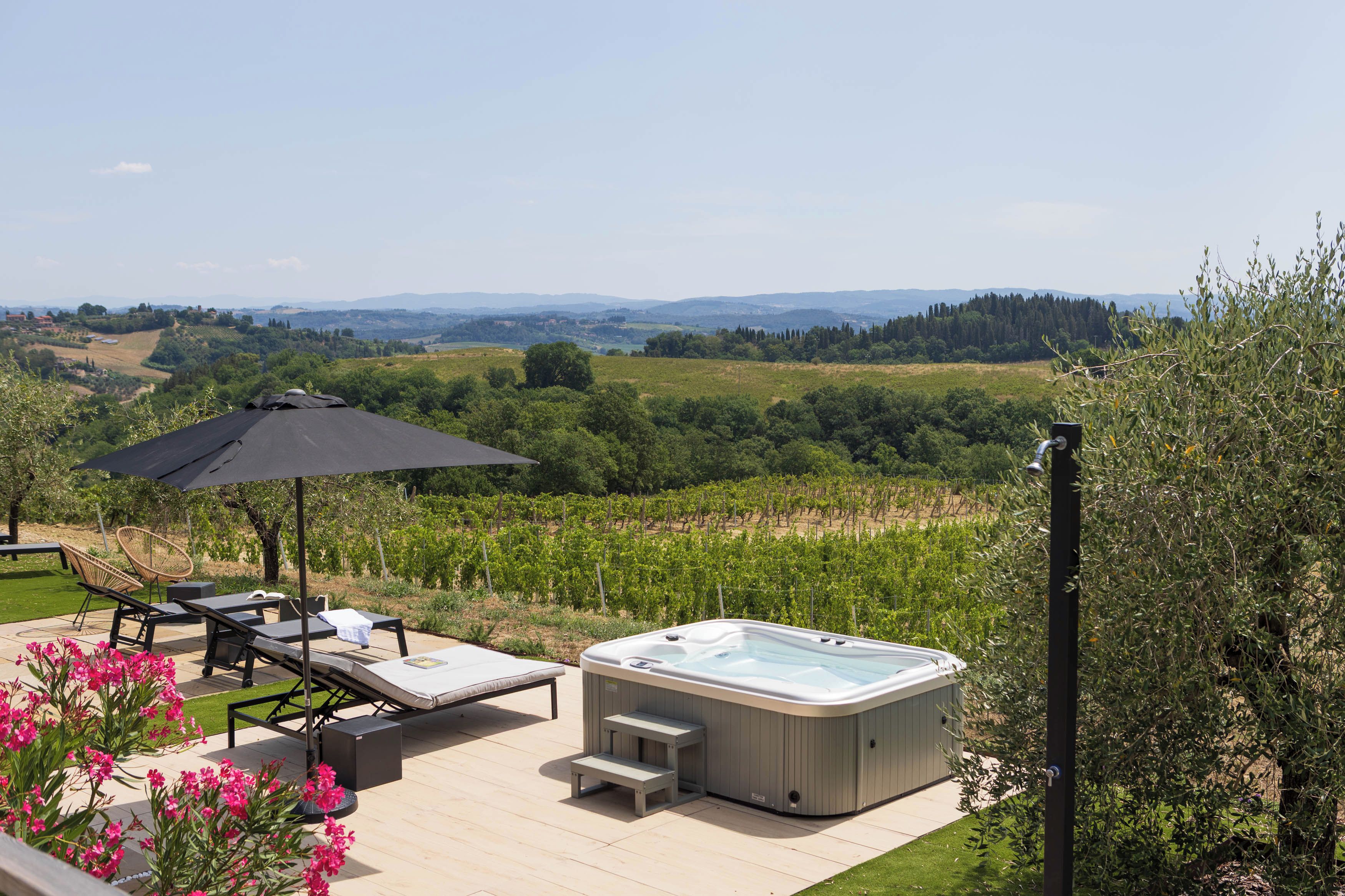 A hot tub on a deck with a view of vineyards and hills.