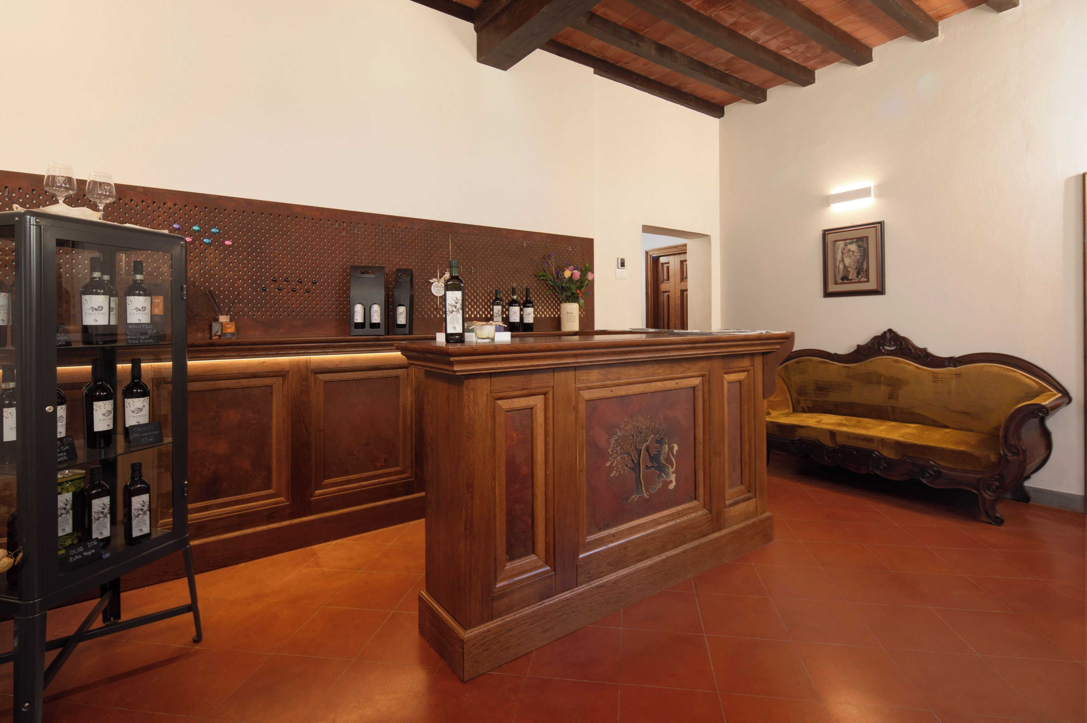 A reception area with a wooden counter, a sofa, and a wine display.