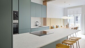 Uma cozinha moderna com ilha central, eletrodomésticos embutidos e uma grande janela que proporciona iluminação natural.