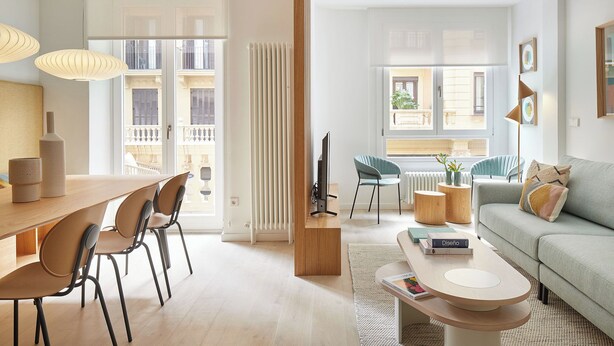 Uma sala de estar moderna com área de jantar, janelas amplas e vista para a cidade.