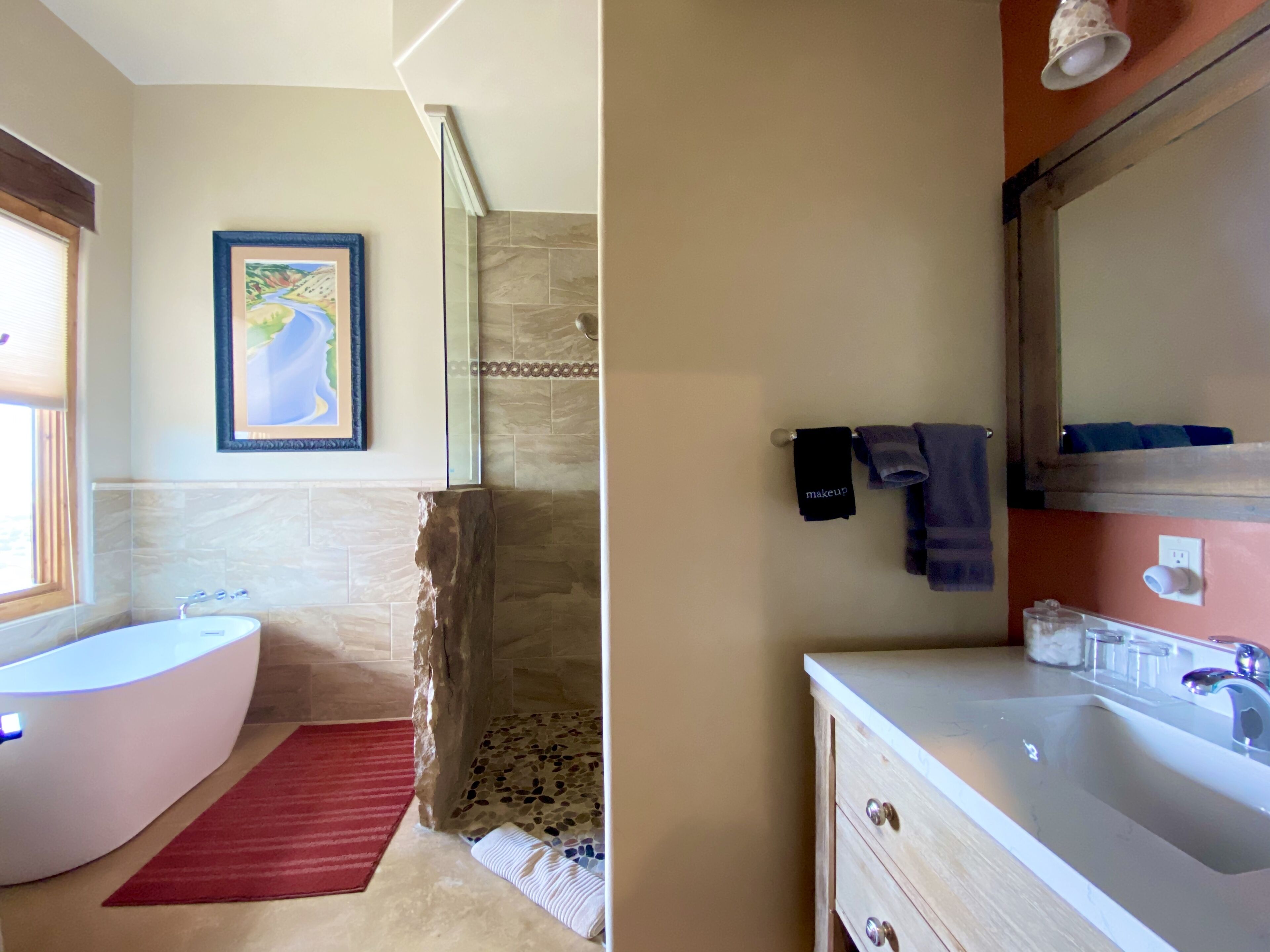 A bathroom with a bathtub, a shower area, and a vanity with a sink.