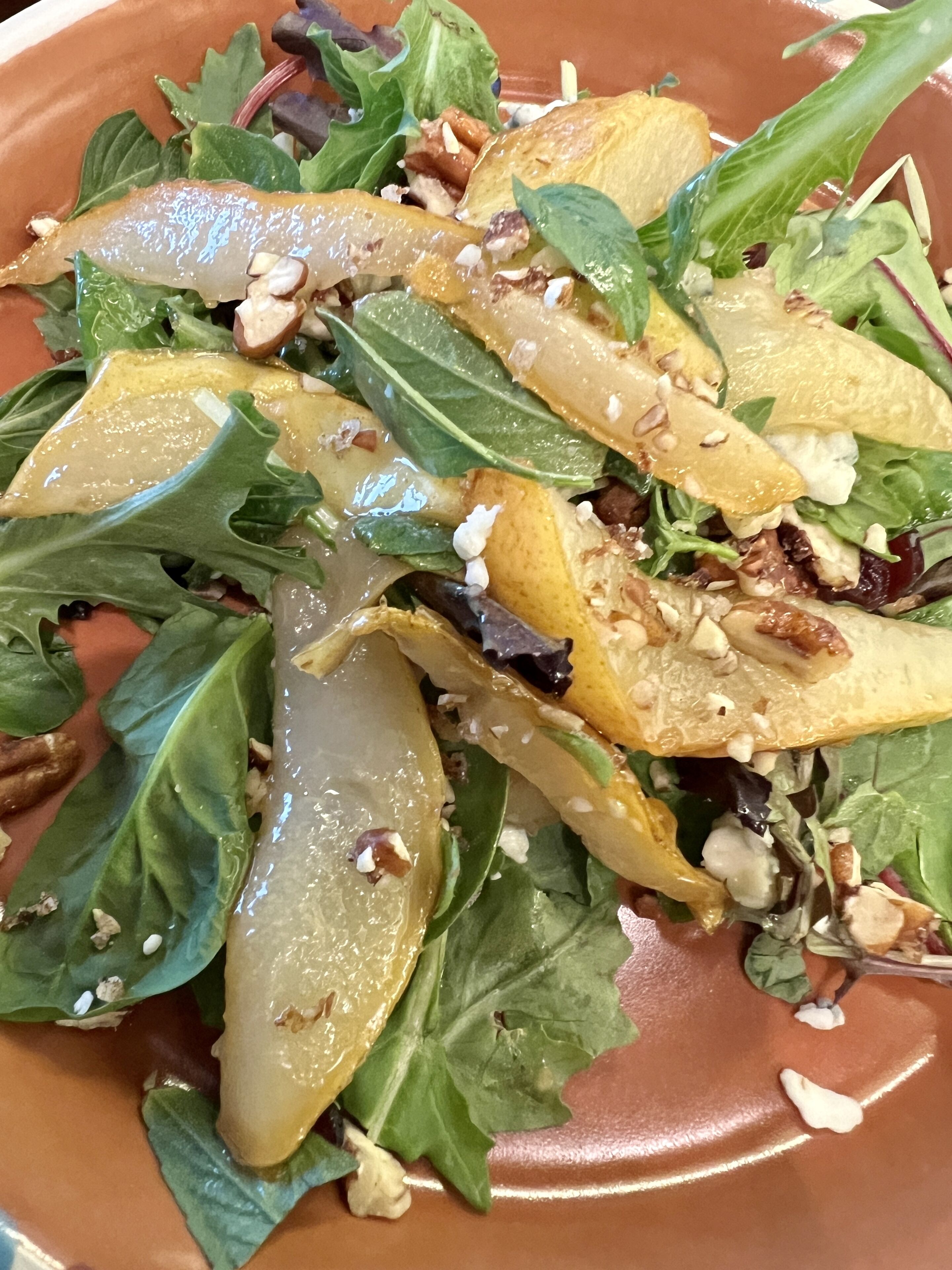Ensalada amb diverses verdures i fruits secs sobre un plat.