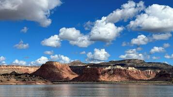 A panoramic view of a canyon with a river in the foreground and mountains in the background.