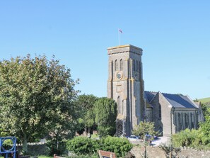 A church with a clock tower, surrounded by greenery and a clear sky. - Mayflower, 9 Coronation Road (Salcombe)