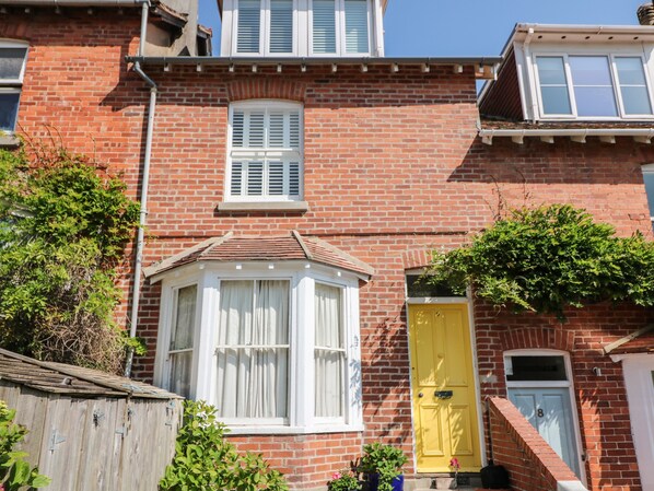 A red brick house with a bay window, a yellow door, and a blue door. - Mayflower, 9 Coronation Road (Salcombe)