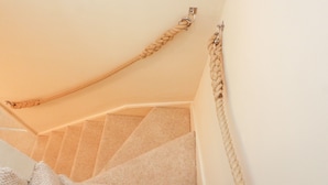 Een trap met een beige tapijt en een beige touwleuning.