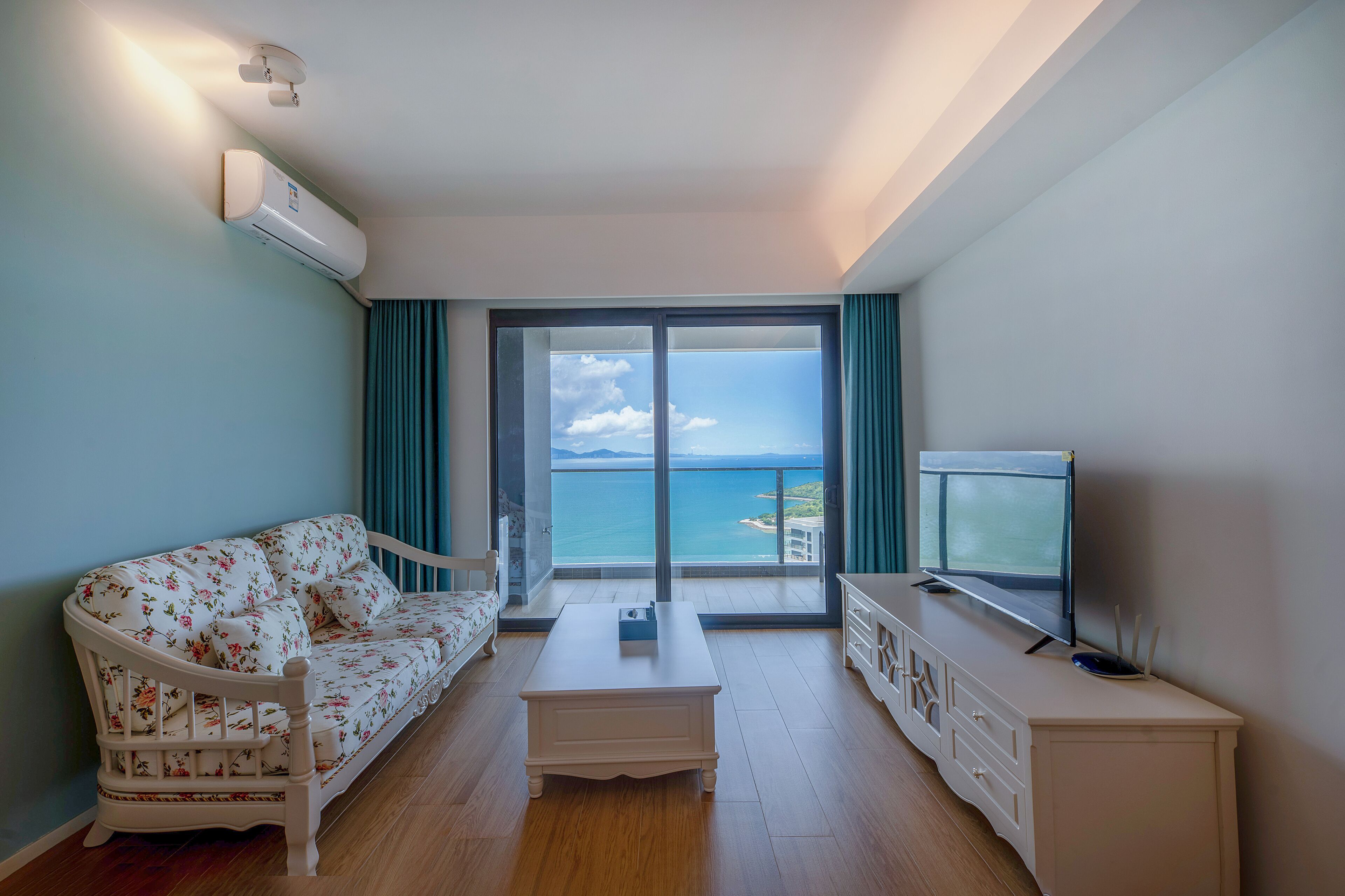 Una habitación con sofá, mesa de centro, televisor y vista al mar.