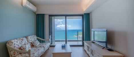 Una habitación con sofá, mesa de centro, televisor y vista al mar.
