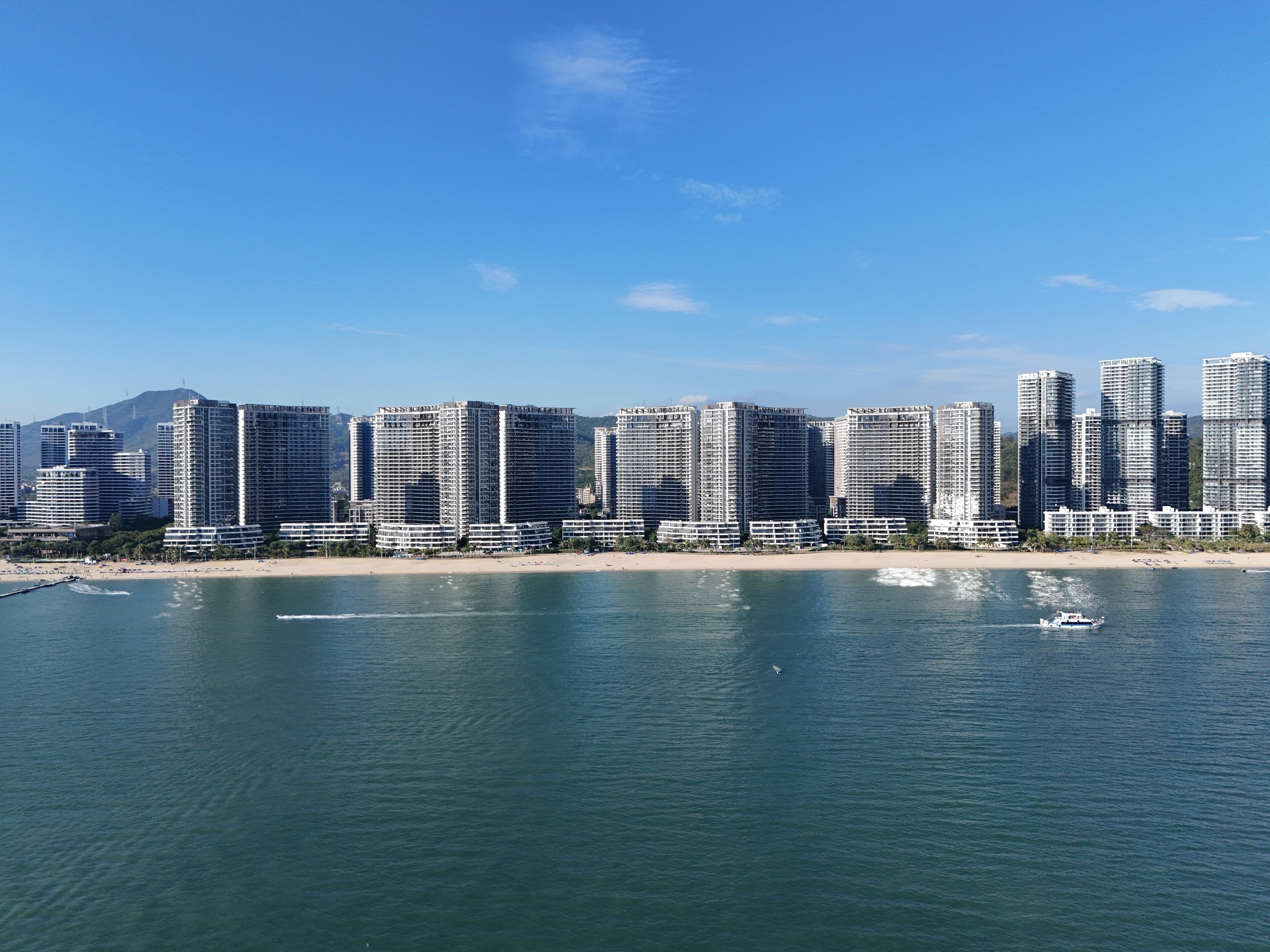 A coastal cityscape with high-rise buildings, a beach, and a calm sea.