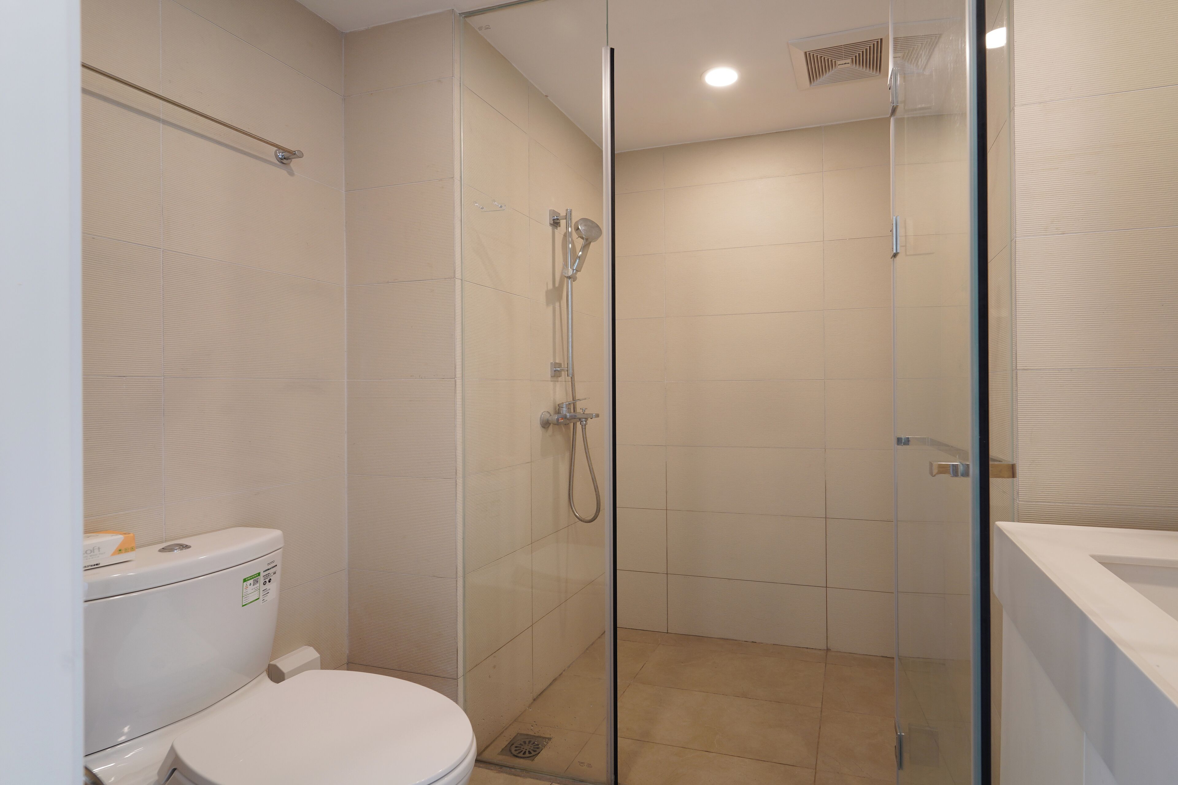 A modern bathroom with a glass-enclosed shower, a toilet, and a sink.
