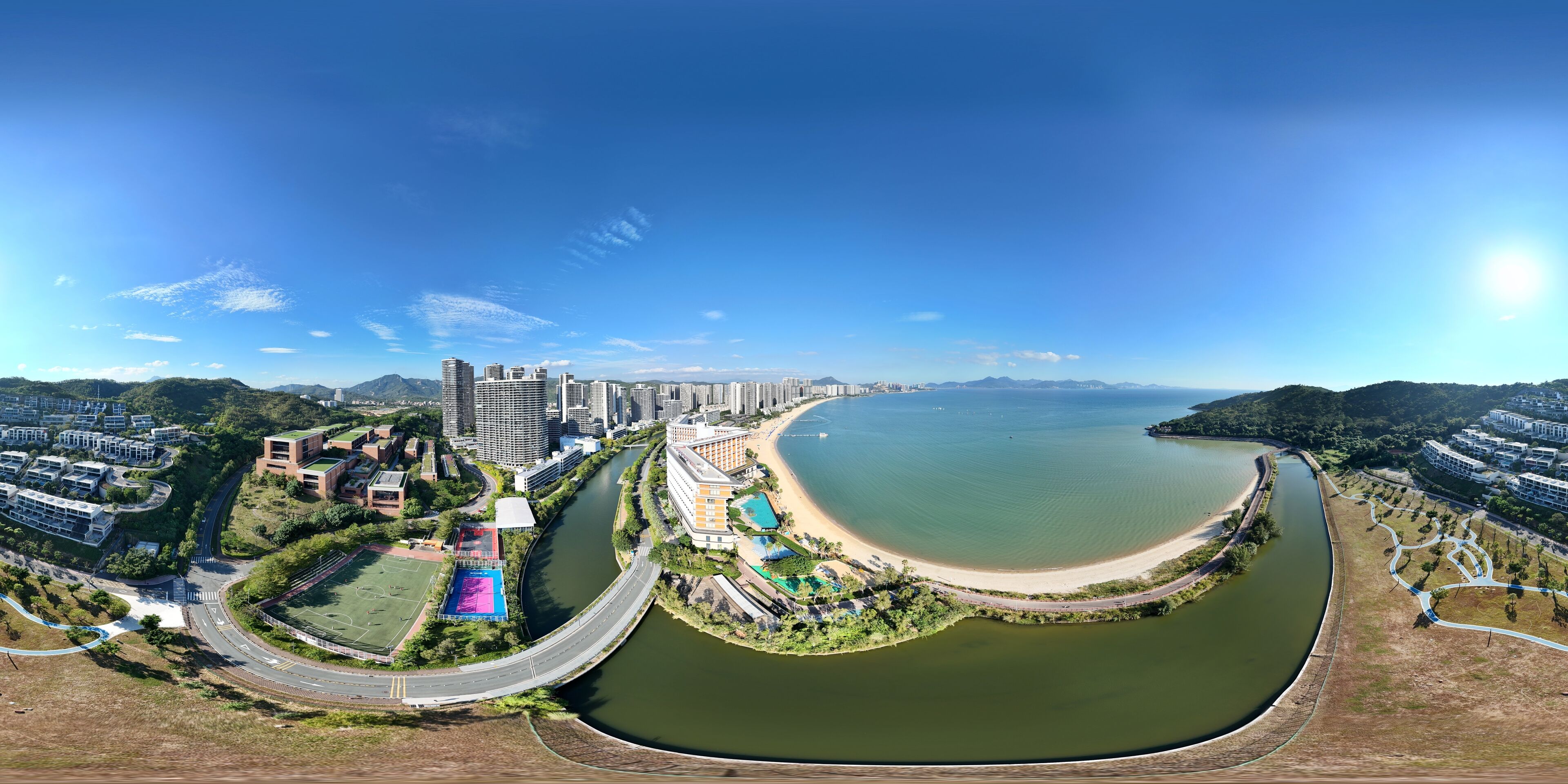 An aerial view of a coastal city with a river, high-rise buildings, and a beach area.