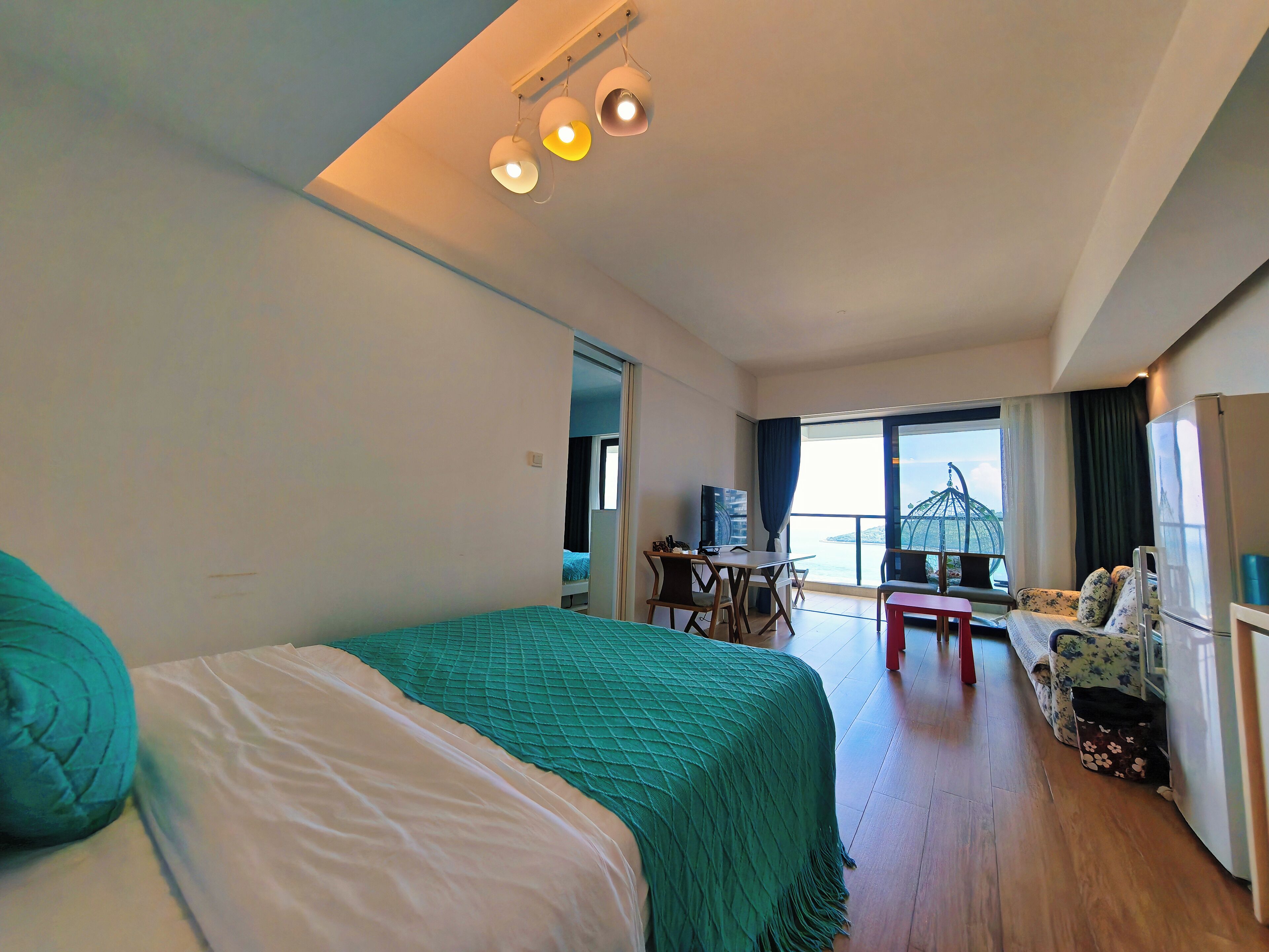 Een hotelkamer met een bed, een bureau, een stoel, een televisie en uitzicht op zee.
