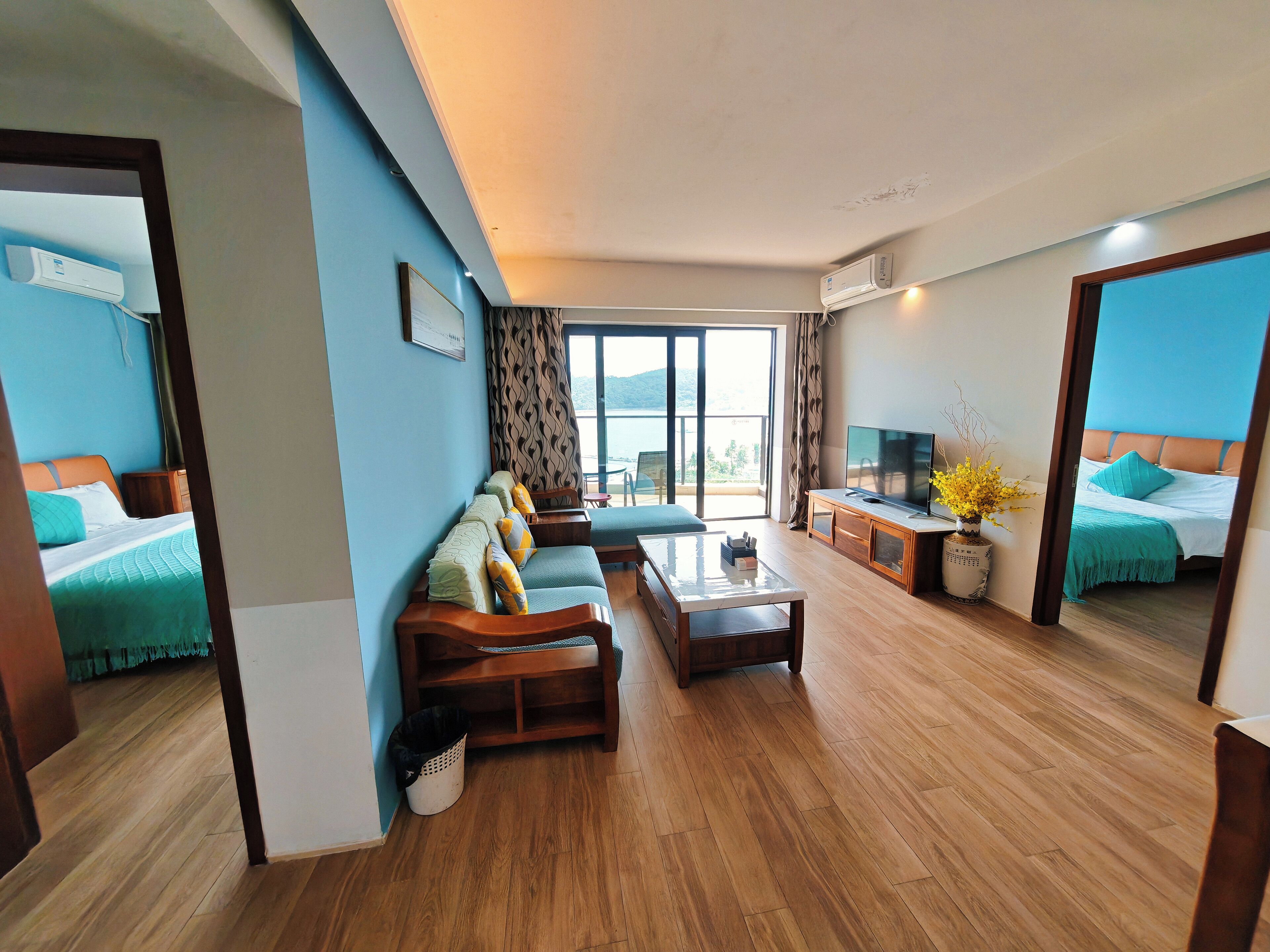 A hotel room with a sofa, a TV, and a balcony with a view.