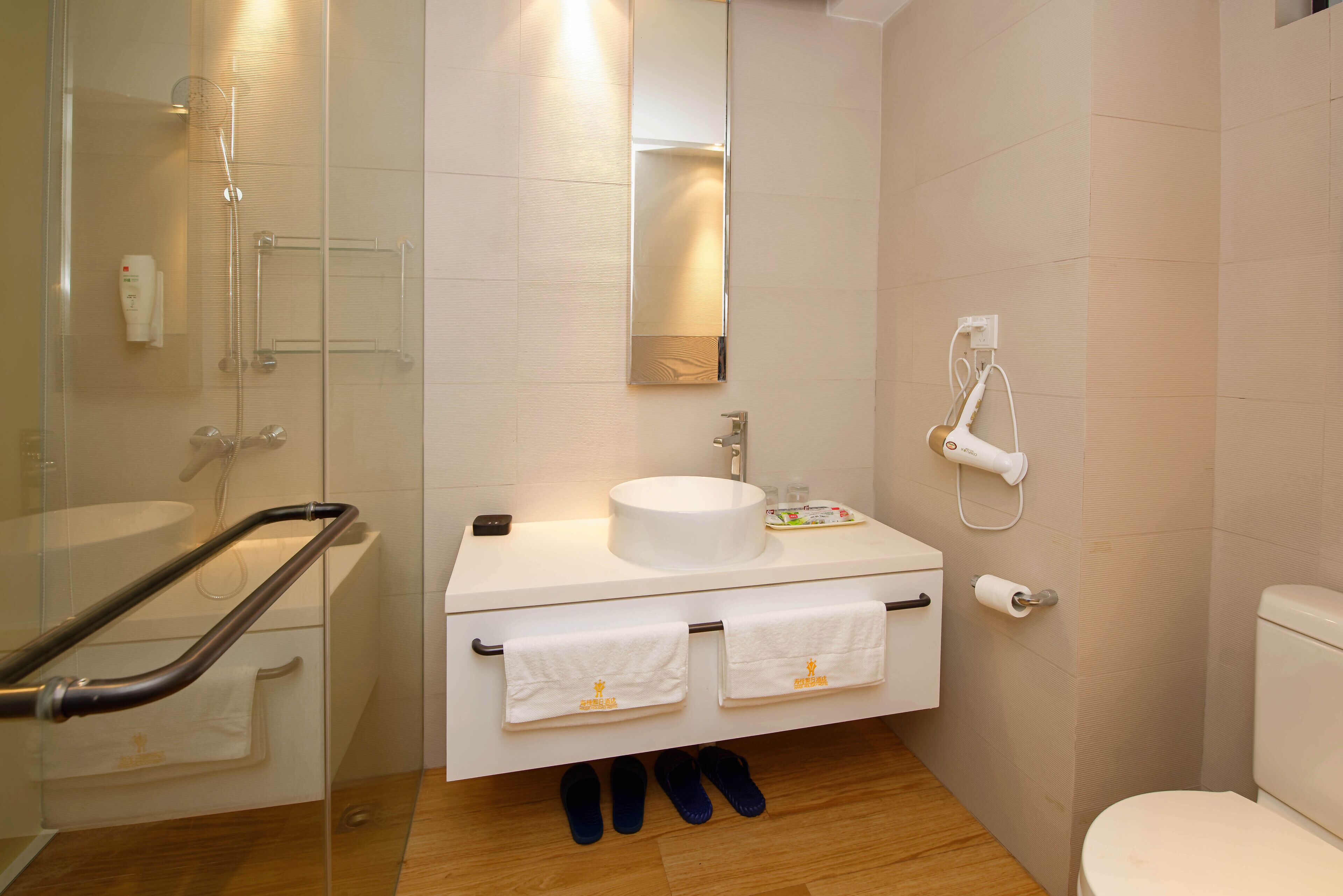 Un baño moderno con cabina de ducha de vidrio, un lavamanos blanco, un espejo y un inodoro.