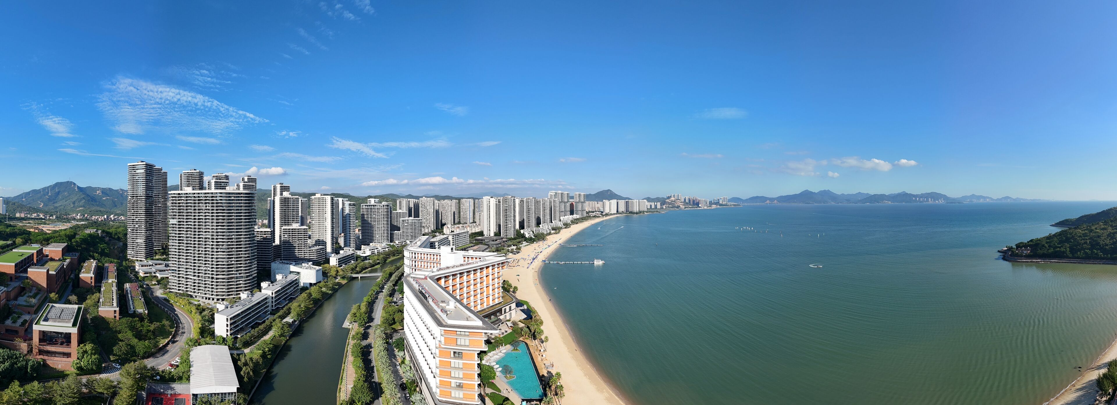 A coastal cityscape with high-rise buildings, a river, and a beach.