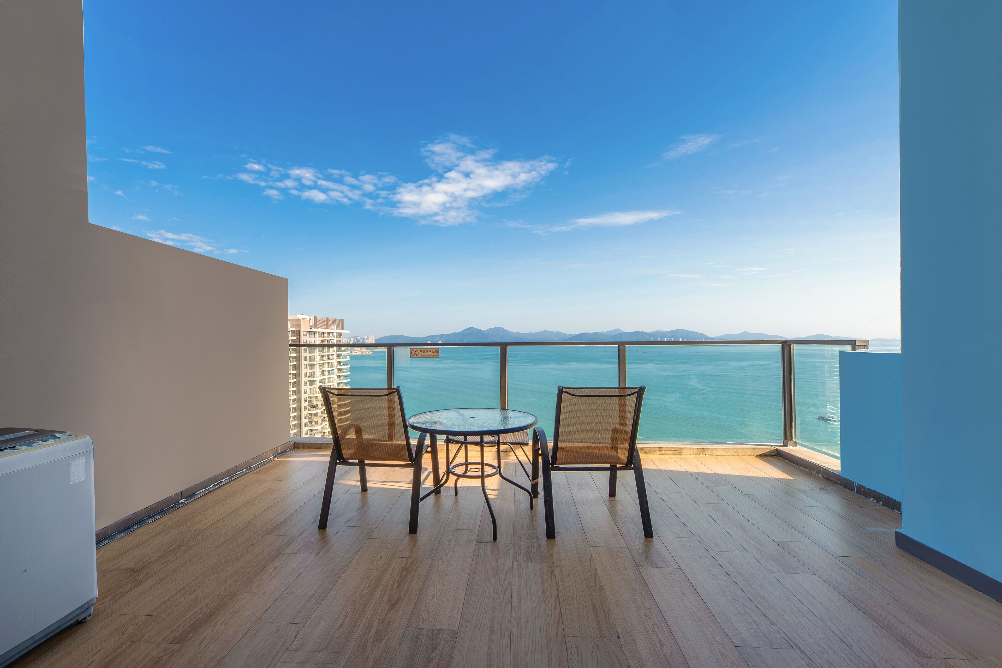 Ein Balkon mit Blick auf das Meer, zwei Korbstühle und ein kleiner Tisch.