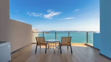 Ein Balkon mit Blick auf das Meer, zwei Korbstühle und ein kleiner Tisch.