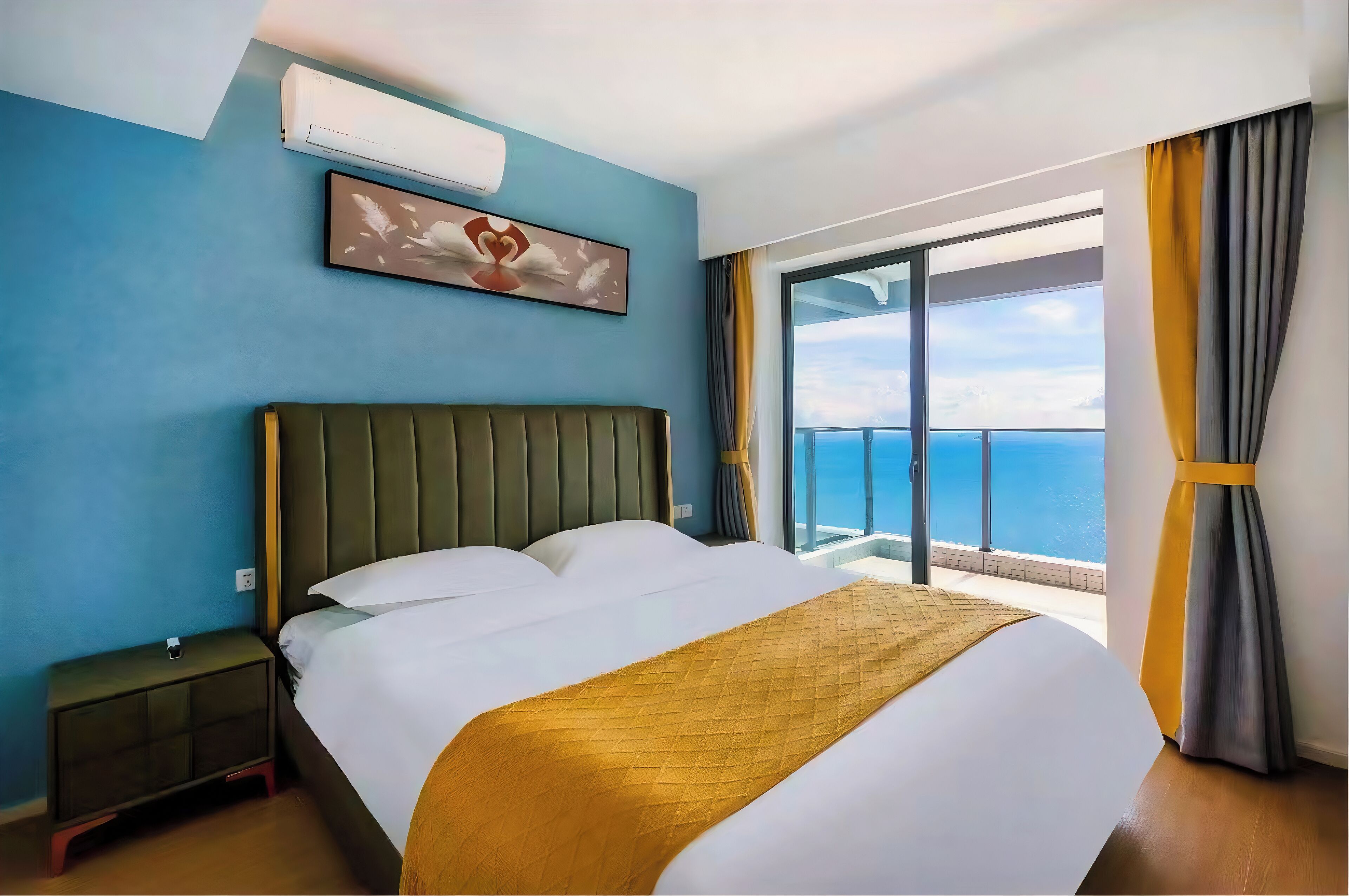 Habitación de hotel con una cama grande, una mesita de noche, un aire acondicionado de pared y una ventana con cortinas.