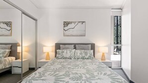 Una camera da letto con un letto grande, due comodini con lampade, uno specchio e opere d'arte alle pareti.