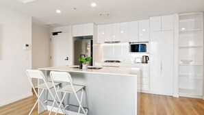 A modern kitchen with white cabinetry, a central island with seating, and a microwave above the island.