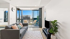 A modern living room with a grey sofa, a flat-screen TV, and a potted plant.