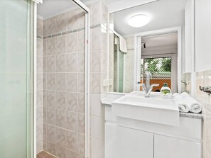 Un baño con ducha, lavabo y espejo.