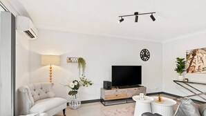 Ein modernes Wohnzimmer mit einer Couch, einem Fernseher, einem Couchtisch und einer Lampe.
