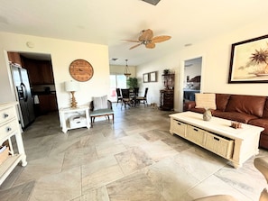A spacious living area with a dining table, chairs, a sofa, a clock, and a ceiling fan. - Pets, Plunges & Peace on the Gulf of Mexico (Nokomis)
